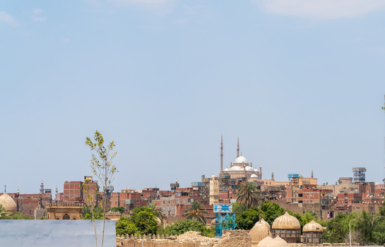 View of the historic Cairo Citadel with its prominent domes and minarets rising above the dense urban landscape of Cairo Egypt.