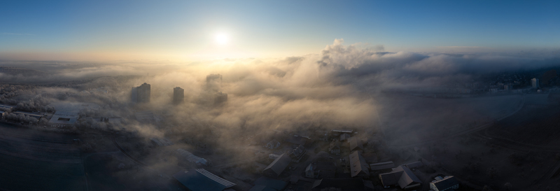 Aerial view of high rise buildings and residential rooftops emerging from thick morning fog under a bright sun in Tubingen Baden Wurttemberg Germany.