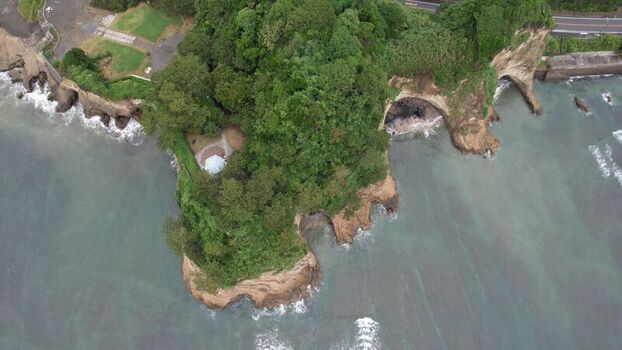 Aerial view of Inamuragasaki headland with lush greenery rocky cliffs and coastal waves in Kamakura Kanagawa Japan.
