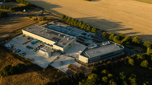 Aerial view of the Moderna Innovation and Technology Centre with industrial buildings parking and surrounding fields under golden hour light in Harwell Oxford England United Kingdom.