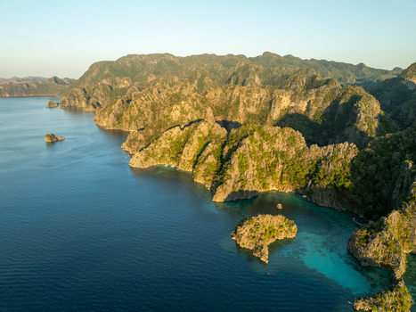 Aerial view of Twin Lagoon featuring dramatic limestone cliffs turquoise waters and lush vegetation under golden hour light in Coron Mimaropa Philippines. Aerial view of Twin Lagoon featuring dramatic limestone cliffs turquoise waters and lush vegetation under golden hour light in Coron Mimaropa Philippines.