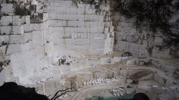 View of a large white marble quarry with heavy machinery in Thasos Greece.