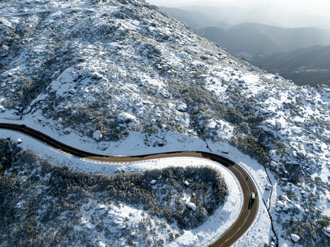 Aerial view of a winding road curves through a snow dusted mountain landscape the stark white contrasting with the dark asphalt São Romão Guarda District Portugal. Aerial view of a winding road curves through a snow dusted mountain landscape the stark white contrasting with the dark asphalt São Romão Guarda District Portugal.