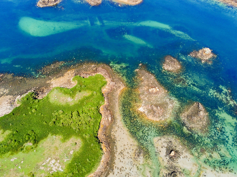 Aerial view of the rugged coastline and rocky islets of Brehat surrounded by turquoise waters and lush green vegetation in Ile de Brehat Brittany France.