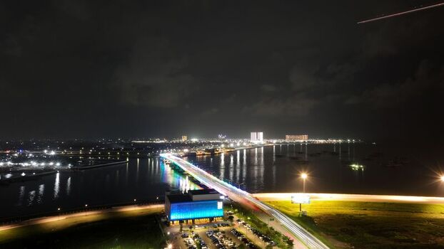 Aerial view of the illuminated Pantai Indah Kapuk 2 bridge at night with vibrant lighting modern buildings and a parking lot in Kecamatan Penjaringan Banten Indonesia. Aerial view of the illuminated Pantai Indah Kapuk 2 bridge at night with vibrant lighting modern buildings and a parking lot in Kecamatan Penjaringan Banten Indonesia.