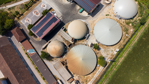 Aerial view of a biomethane production facility with large storage tanks solar panels on rooftops and surrounding agricultural fields in Tavazzano con Villavesco Lombardy Italy.