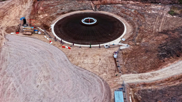 Aerial view of a wind turbine foundation under construction with a circular rebar structure on a dirt site in Latvia. Aerial view of a wind turbine foundation under construction with a circular rebar structure on a dirt site in Latvia.