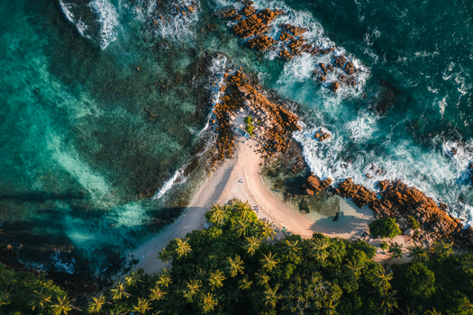 Aerial view of Secret Beach Mirissa featuring turquoise water rocky coastline sandy beach and lush palm trees in Mirissa Southern Province Sri Lanka. Aerial view of Secret Beach Mirissa featuring turquoise water rocky coastline sandy beach and lush palm trees in Mirissa Southern Province Sri Lanka.