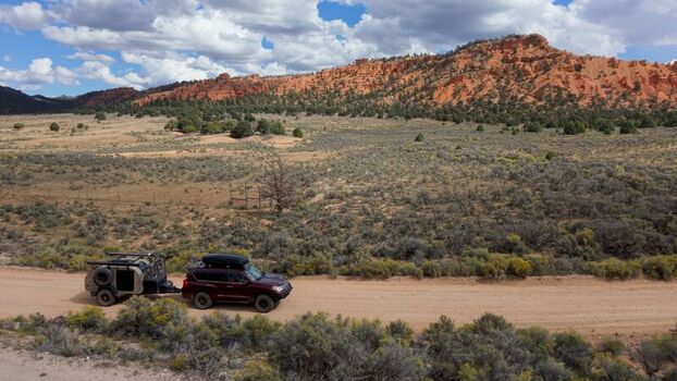 Aerial view of an SUV pulling a teardrop camper trailer on a dirt road through the red rock landscape of Costa Canyon near Bryce Canyon Panguitch Utah United States.