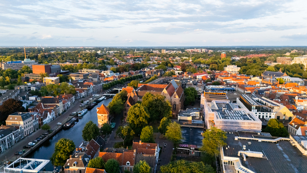 Aerial view of the historic city of Zwolle with its iconic Sassenpoort gate winding canal and dense urban rooftops bathed in warm golden hour light in Zwolle Overijssel Netherlands.