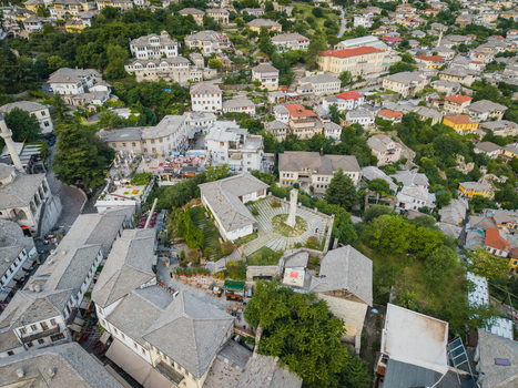Aerial view of the historic old town featuring traditional stone houses with slate roofs and a central monument square in Gjirokaster Gjirokaster County Albania. Aerial view of the historic old town featuring traditional stone houses with slate roofs and a central monument square in Gjirokaster Gjirokaster County Albania.