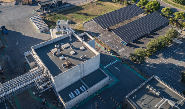 Aerial view of an industrial facility featuring a large solar photovoltaic carport concrete process buildings and infrastructure in Le Pouzin Auvergne Rhone Alpes France.