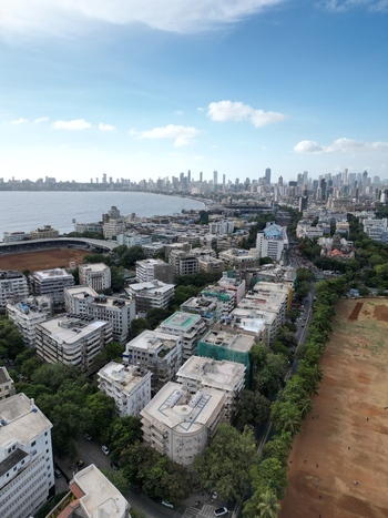Aerial view of the coastal skyline and urban landscape with residential buildings and green trees along the bay in Mumbai Maharashtra India.