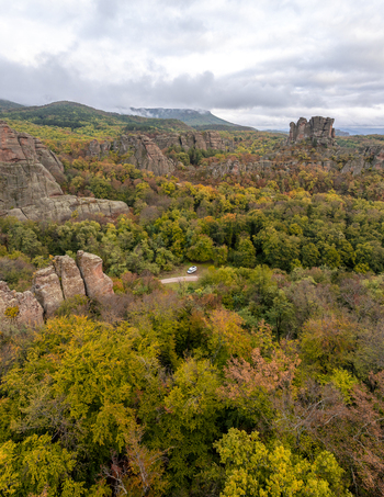 Aerial view of the Belogradchik Rocks surrounded by dense autumn forests with vibrant foliage and dramatic rock formations under a cloudy sky in Belogradchik Vidin Bulgaria. Aerial view of the Belogradchik Rocks surrounded by dense autumn forests with vibrant foliage and dramatic rock formations under a cloudy sky in Belogradchik Vidin Bulgaria.