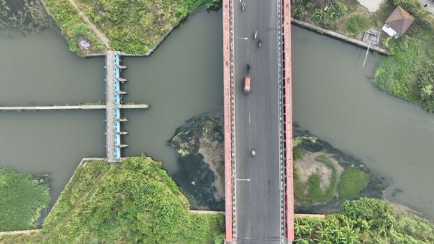 Aerial view of a bridge crossing a river with a small weir structure and lush green vegetation in Bekasi Barat West Java Indonesia. Aerial view of a bridge crossing a river with a small weir structure and lush green vegetation in Bekasi Barat West Java Indonesia.