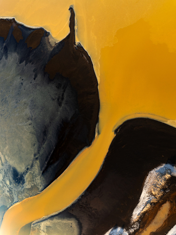 Aerial view of the abstract patterns of a geothermal river flowing through dark volcanic terrain in Reykjanesbaer Iceland. Aerial view of the abstract patterns of a geothermal river flowing through dark volcanic terrain in Reykjanesbaer Iceland.