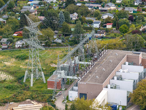 Aerial view of Umspannwerk Reuter electrical substation with high voltage transmission towers and industrial infrastructure near residential houses and trees in Berlin Berlin Germany.