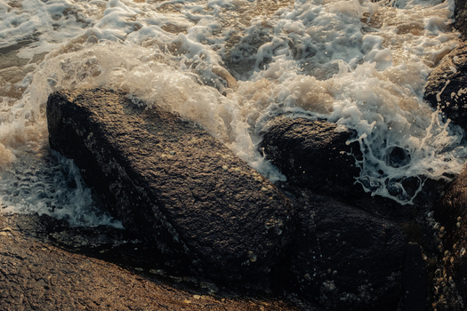 View of frothy white capped waves crashing against dark textured rocks a dance of nature s raw power and serene beauty Chiplun Maharashtra India. View of frothy white capped waves crashing against dark textured rocks a dance of nature s raw power and serene beauty Chiplun Maharashtra India.
