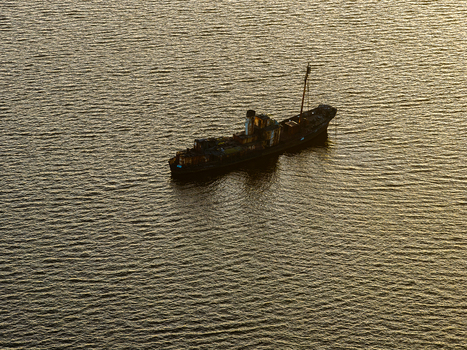 Aerial view of a rusted shipwreck floating in calm waters during golden hour near the coast of Vancouver Peninsula Western Australia Australia. Aerial view of a rusted shipwreck floating in calm waters during golden hour near the coast of Vancouver Peninsula Western Australia Australia.