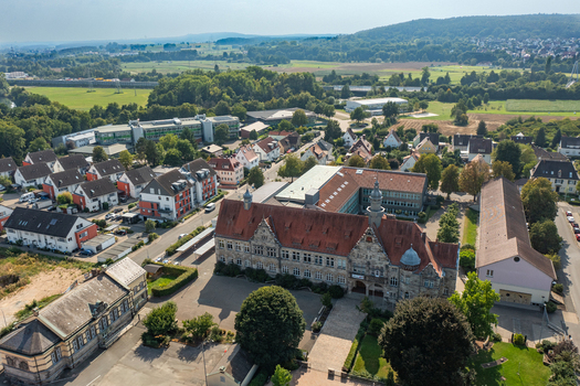 Aerial view of the Herder Gymnasium school building with its historic stone facade and red tiled roofs surrounded by residential houses and green trees in Forchheim Bayern Germany.