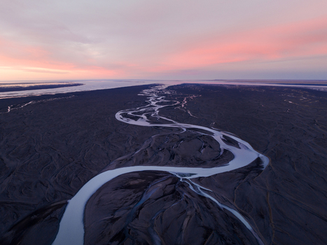 Aerial view of a glacial river meanders through a stark landscape its icy waters reflecting the soft hues of dawn in Iceland. Iceland Iceland. Aerial view of a glacial river meanders through a stark landscape its icy waters reflecting the soft hues of dawn in Iceland. Iceland Iceland.