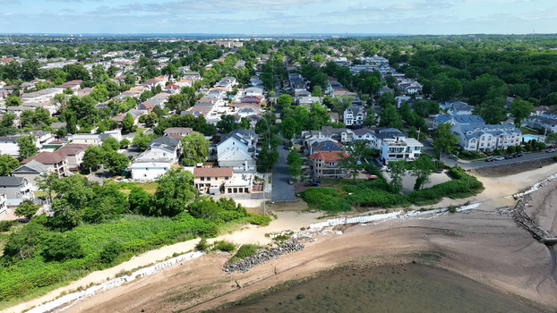 Aerial view of the residential neighborhood of Tottenville in Staten Island with houses lush trees and a sandy coastline along the water in New York New York United States. Aerial view of the residential neighborhood of Tottenville in Staten Island with houses lush trees and a sandy coastline along the water in New York New York United States.