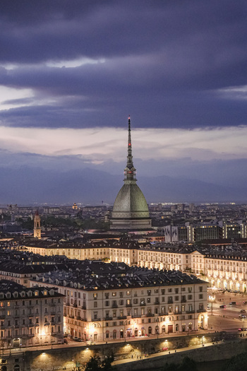 Aerial view of the Mole Antonelliana towering over the illuminated historic city center under a dramatic twilight sky in Turin Piedmont Italy. Aerial view of the Mole Antonelliana towering over the illuminated historic city center under a dramatic twilight sky in Turin Piedmont Italy.