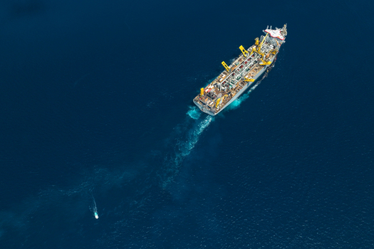 Aerial view of a large dredger vessel and a dhoni navigating through deep blue ocean waters leaving a white wake Vashafaru Haa Alif Atoll Maldives. Aerial view of a large dredger vessel and a dhoni navigating through deep blue ocean waters leaving a white wake Vashafaru Haa Alif Atoll Maldives.