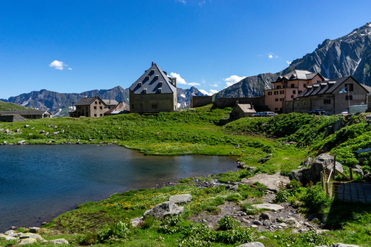View of the historic stone buildings at Sankt Gotthard Pass overlooking a mountain lake and green meadows in Airolo Ticino Switzerland.