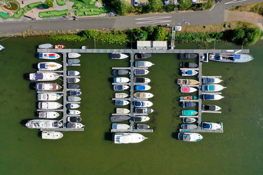 Aerial view of a marina with numerous motorboats and yachts docked at wooden piers on the green water of the Main river in Aschaffenburg Bayern Germany. Aerial view of a marina with numerous motorboats and yachts docked at wooden piers on the green water of the Main river in Aschaffenburg Bayern Germany.