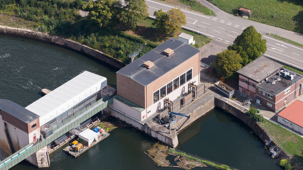 Aerial view of the Neckar Staustufe und Schleuse Rockenau lock and dam facility on the Neckar river featuring industrial brick buildings and infrastructure in Eberbach Baden Wurttemberg Germany.