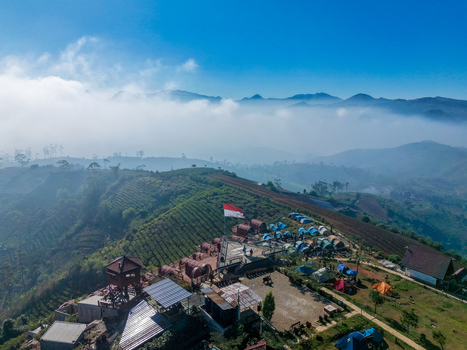 Aerial view of Sunrise Point Cukul with its camping area and Indonesian flag set amidst lush tea plantations and misty mountains in Kecamatan Pangalengan Jawa Barat Indonesia. Aerial view of Sunrise Point Cukul with its camping area and Indonesian flag set amidst lush tea plantations and misty mountains in Kecamatan Pangalengan Jawa Barat Indonesia.