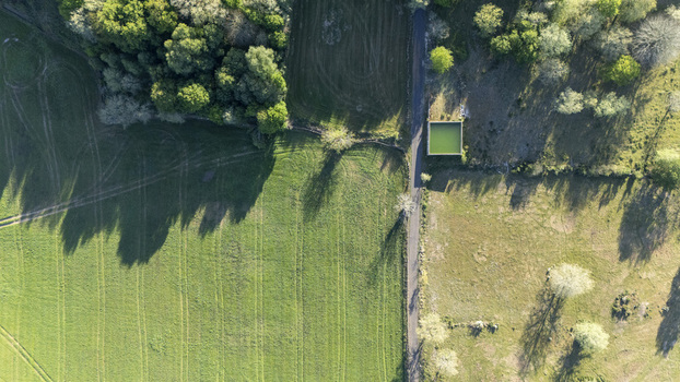 Aerial view of lush green agricultural fields a narrow rural road and a square green water tank surrounded by trees in Ourense Province of Ourense Spain. Aerial view of lush green agricultural fields a narrow rural road and a square green water tank surrounded by trees in Ourense Province of Ourense Spain.