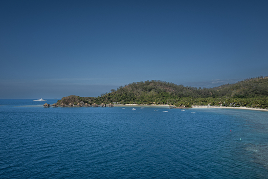 Aerial view of Likuliku Lagoon Resort with overwater bungalows turquoise lagoon and lush tropical hills in Yaro Nadroga Navosa Fiji.