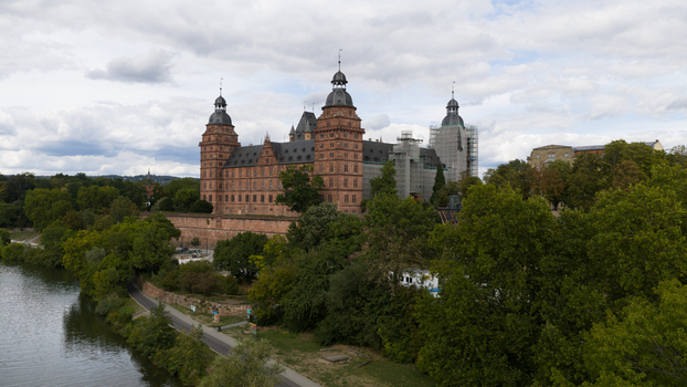 Aerial view of the historic red sandstone Schloss Johannisburg castle surrounded by lush green trees and the river Main in Aschaffenburg Bayern Germany.