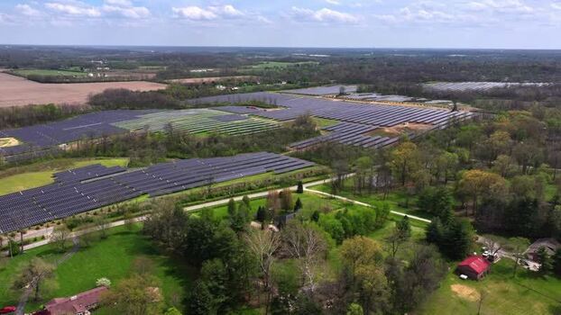 Aerial view of a large solar farm surrounded by green trees United States. Aerial view of a large solar farm surrounded by green trees United States.