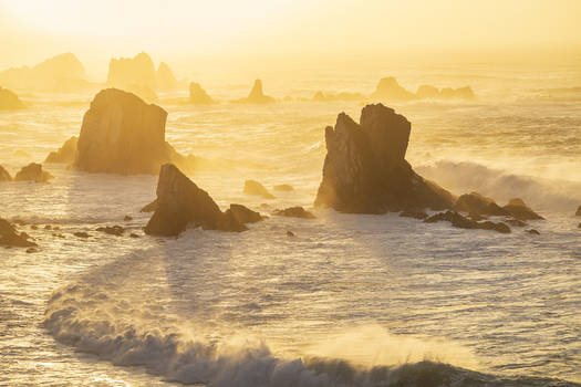 View of Silence Beach featuring jagged rock formations and crashing waves under the warm glow of a golden sunset Asturias Asturias Spain.