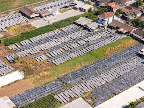Aerial view of UKM Sohun production facility with rows of drying sohun noodles on trays in an open field surrounded by rural buildings and greenery in Kecamatan Tulung Jawa Tengah Indonesia.