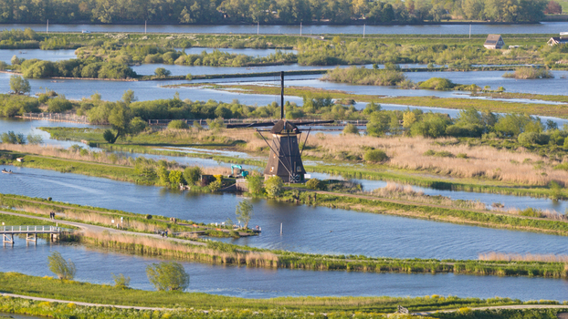 Aerial view of a historic windmill surrounded by winding canals lush green wetlands and walking paths Kinderdijk South Holland Netherlands. Aerial view of a historic windmill surrounded by winding canals lush green wetlands and walking paths Kinderdijk South Holland Netherlands.