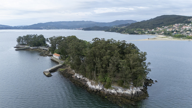 Aerial view of Illa de San Simon with its dense green trees historic stone walls and small buildings surrounded by the calm waters of the bay in Pontevedra Pontevedra Spain. Aerial view of Illa de San Simon with its dense green trees historic stone walls and small buildings surrounded by the calm waters of the bay in Pontevedra Pontevedra Spain.