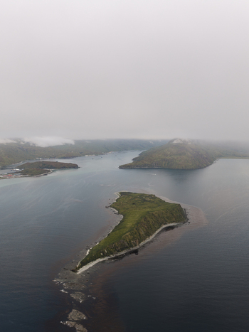 Aerial view of the rugged coastline and green islands of Unalaska Bay under a cloudy sky in Unalaska Alaska United States.