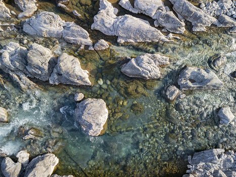 Aerial view of Lume i Kirit with clear turquoise water flowing over smooth grey river stones and boulders in Shkoder Qarku i Shkodres Albania. Aerial view of Lume i Kirit with clear turquoise water flowing over smooth grey river stones and boulders in Shkoder Qarku i Shkodres Albania.