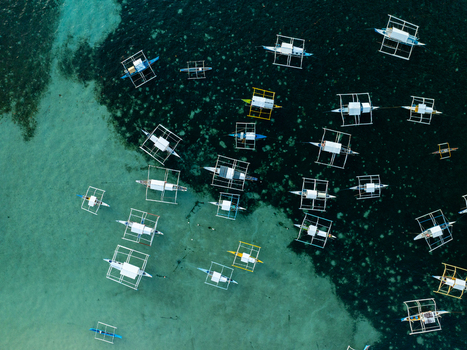 Aerial view of Naked Island surrounded by numerous traditional outrigger boats floating in the clear turquoise waters of Siargao Philippines. Aerial view of Naked Island surrounded by numerous traditional outrigger boats floating in the clear turquoise waters of Siargao Philippines.