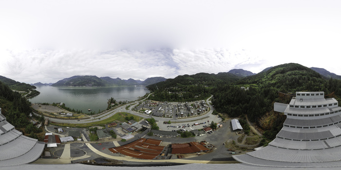 Aerial view of a large industrial facility and residential complex situated along a coastal highway with mountains and water in the background in Metro Vancouver A British Columbia Canada.
