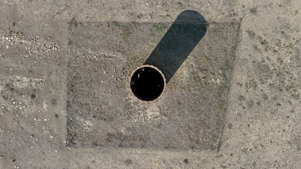 Aerial view of a circular structure enclosed within a square fence set in a dry arid landscape in Golden Colorado United States.
