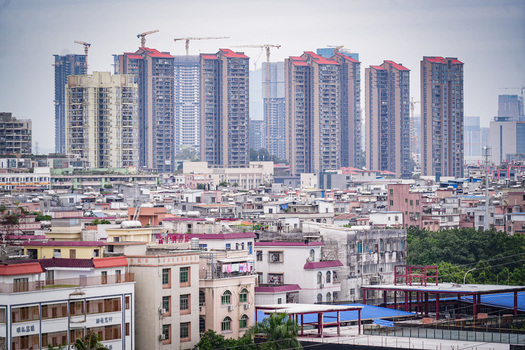 Aerial view of modern high rise residential towers rising above dense low rise urban neighborhoods with construction cranes in Guangzhou Guangdong Province China. Aerial view of modern high rise residential towers rising above dense low rise urban neighborhoods with construction cranes in Guangzhou Guangdong Province China.