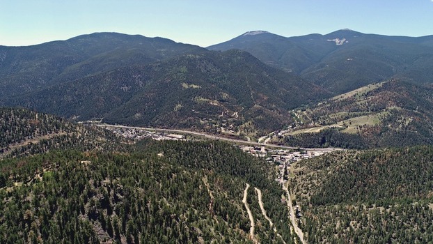 Aerial view of Virginia Canyon with winding roads dense pine forests and the town of Idaho Springs nestled in the valley under a clear blue sky in Idaho Springs Colorado United States. Aerial view of Virginia Canyon with winding roads dense pine forests and the town of Idaho Springs nestled in the valley under a clear blue sky in Idaho Springs Colorado United States.