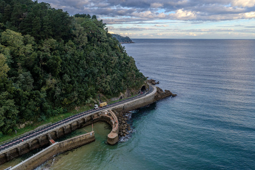 Aerial view of Puerto de Zarautz featuring a coastal road winding along the cliffside with a tunnel entrance overlooking the sea in Zarautz Basque Country Spain.