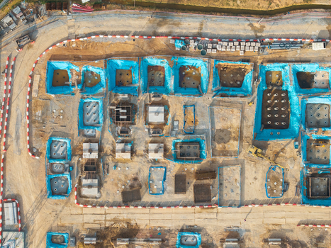 Aerial view of a construction site featuring foundation pits lined with blue plastic sheeting concrete footings and heavy machinery in Bukit Tambun Penang Malaysia. Aerial view of a construction site featuring foundation pits lined with blue plastic sheeting concrete footings and heavy machinery in Bukit Tambun Penang Malaysia.