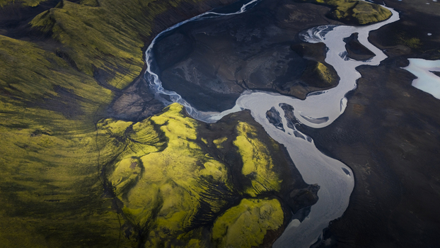 Aerial view of the glacial river Langisjor winding through vibrant moss covered volcanic terrain in Vik Skaftarhreppur Iceland. Aerial view of the glacial river Langisjor winding through vibrant moss covered volcanic terrain in Vik Skaftarhreppur Iceland.